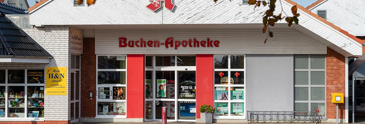 Außenansicht der Buchen-Apotheke in Sanitz mit Eingang, Schaufenstern und Apotheke-Logo über dem Eingang.